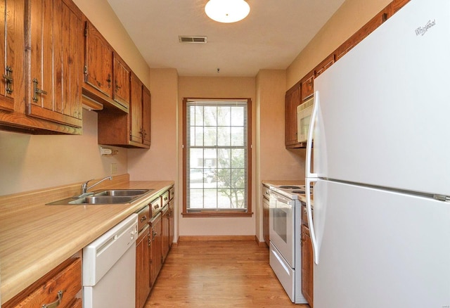 kitchen featuring visible vents, brown cabinetry, white appliances, light countertops, and a sink
