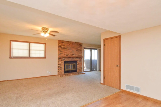 unfurnished living room featuring visible vents, baseboards, a brick fireplace, and ceiling fan
