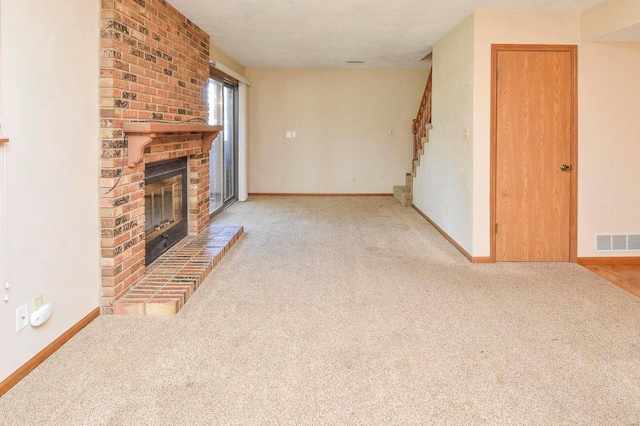 unfurnished living room featuring carpet floors, visible vents, and a brick fireplace