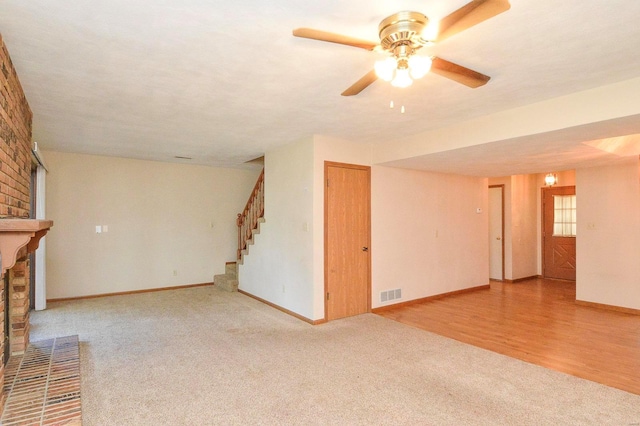 unfurnished living room with visible vents, stairs, a brick fireplace, baseboards, and carpet