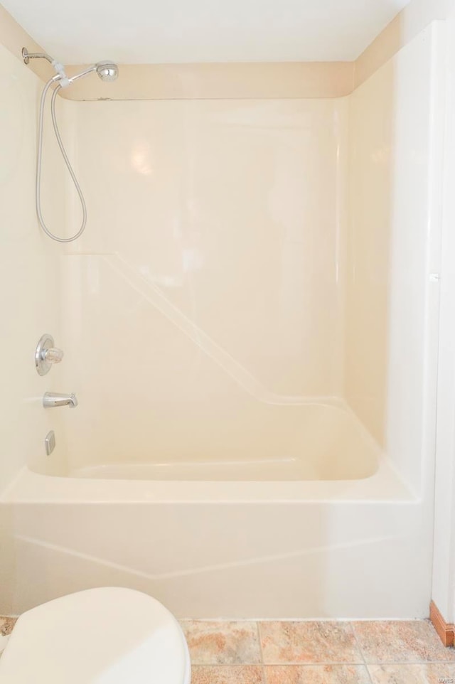 bathroom featuring washtub / shower combination, baseboards, and toilet