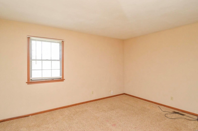 spare room with light colored carpet and baseboards