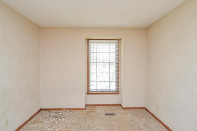 spare room with baseboards, plenty of natural light, light colored carpet, and visible vents