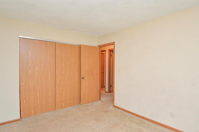 unfurnished bedroom with carpet flooring, baseboards, and a closet