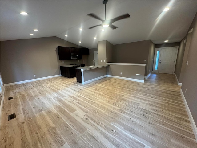 kitchen featuring a ceiling fan, open floor plan, light wood finished floors, and a peninsula