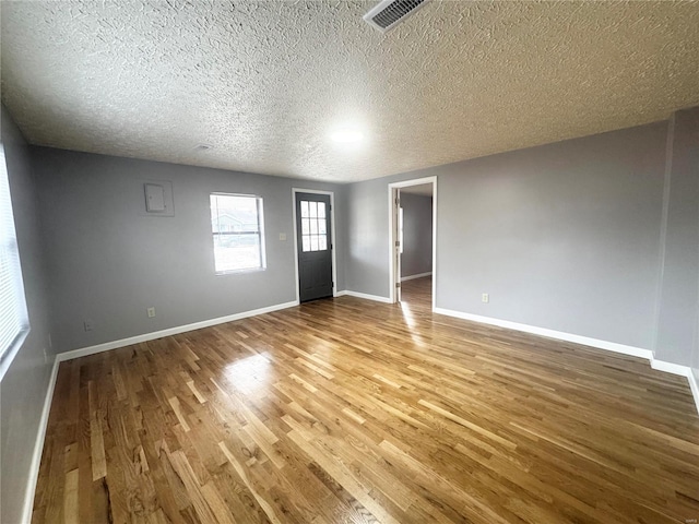 interior space featuring visible vents, baseboards, a textured ceiling, and wood finished floors
