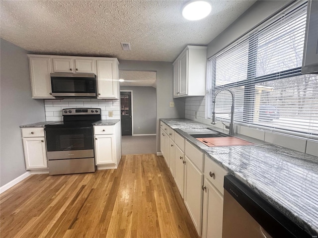 kitchen with appliances with stainless steel finishes, baseboards, decorative backsplash, and a textured ceiling