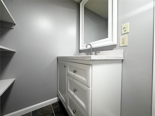 bathroom with baseboards, tile patterned floors, and vanity