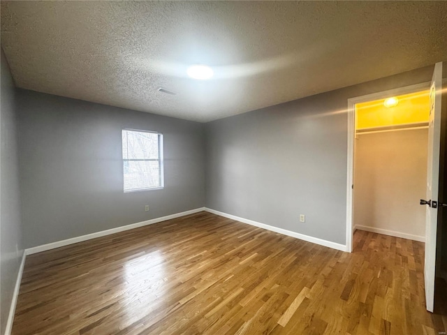 empty room with baseboards, a textured ceiling, and wood finished floors