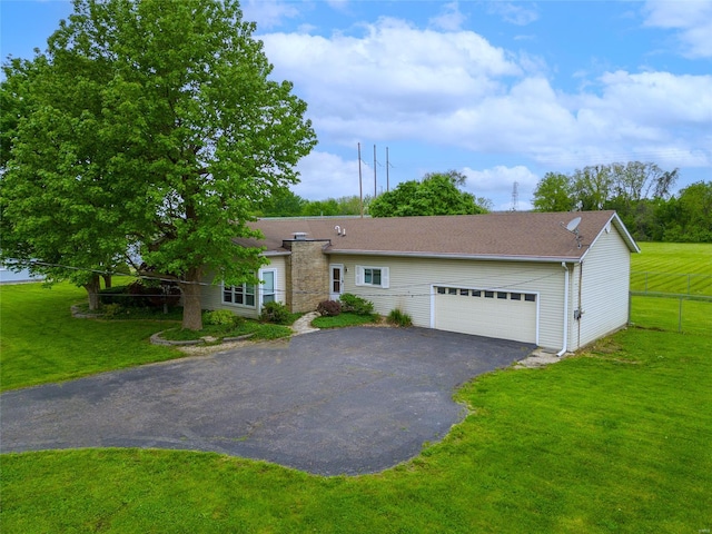 ranch-style home with fence, an attached garage, driveway, and a front lawn