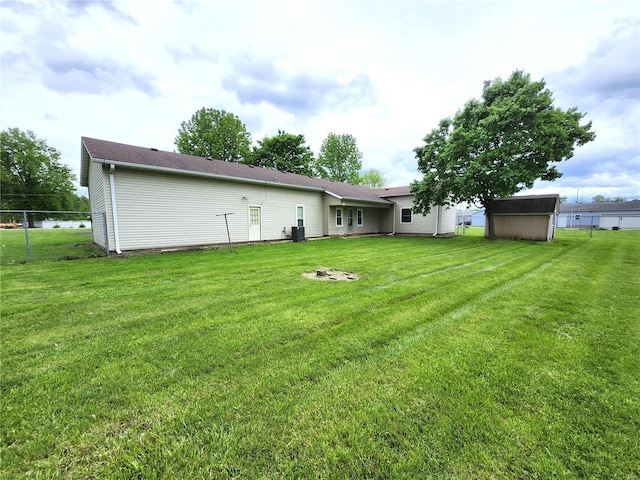 back of property with a lawn, a storage unit, an outdoor structure, and fence