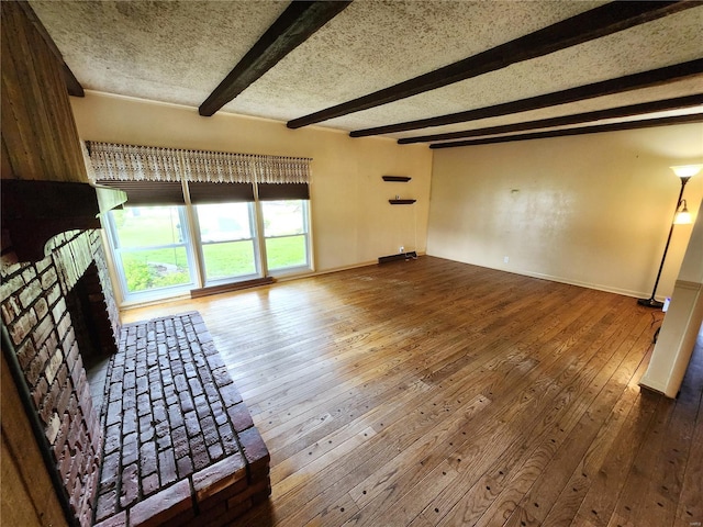 unfurnished living room featuring a fireplace, beamed ceiling, baseboards, and hardwood / wood-style floors