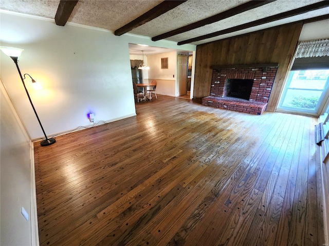 unfurnished living room featuring a fireplace, beamed ceiling, and hardwood / wood-style flooring