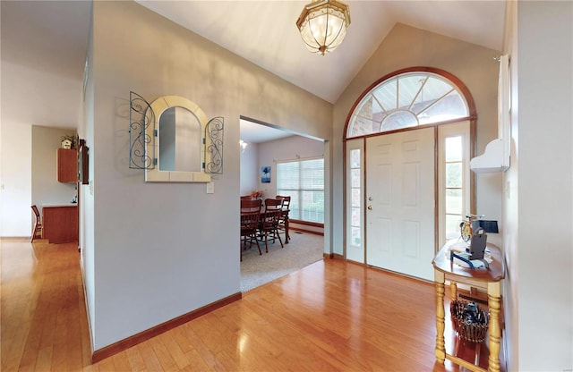 entryway featuring baseboards, wood finished floors, and high vaulted ceiling