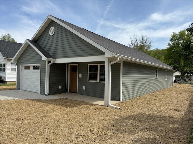 view of front of home featuring an attached garage and a shingled roof