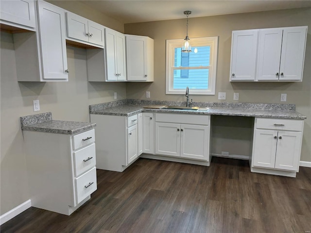 kitchen featuring a sink, decorative light fixtures, white cabinetry, and dark wood-type flooring