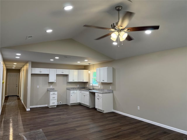 kitchen with a ceiling fan, lofted ceiling, baseboards, white cabinetry, and a sink
