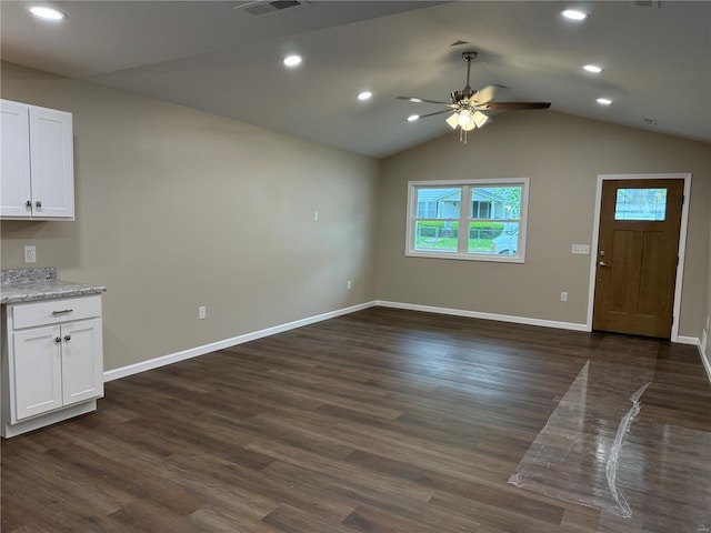 unfurnished living room with visible vents, baseboards, dark wood-style floors, a ceiling fan, and vaulted ceiling