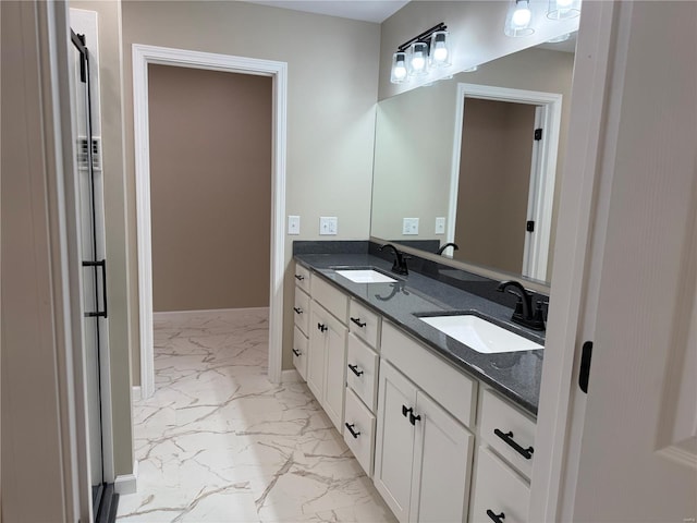 bathroom with double vanity, a sink, marble finish floor, and baseboards