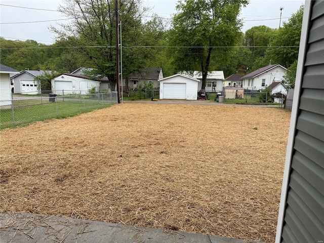 view of yard with a detached garage, fence, a residential view, and driveway