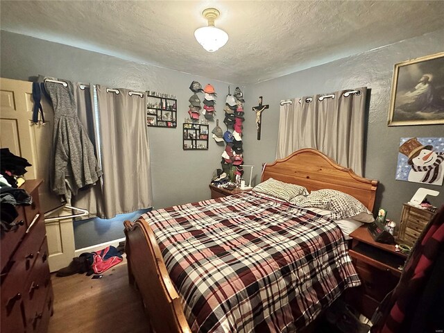 bedroom with a textured ceiling and wood finished floors