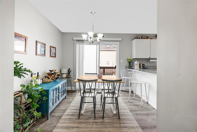 dining space featuring baseboards, wood finished floors, and a notable chandelier