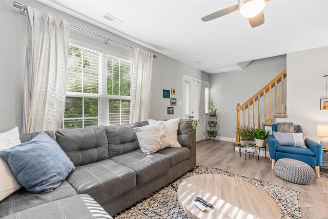 living area with a ceiling fan, visible vents, wood finished floors, and stairway