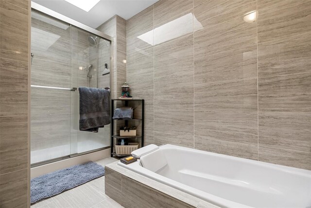 full bath featuring tile walls, a stall shower, and a bath