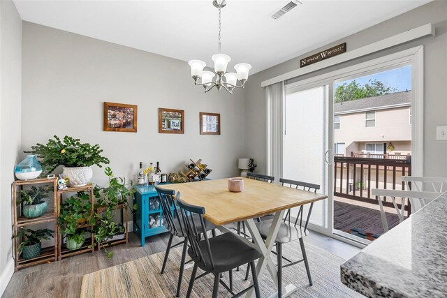 dining room featuring an inviting chandelier, baseboards, wood finished floors, and visible vents