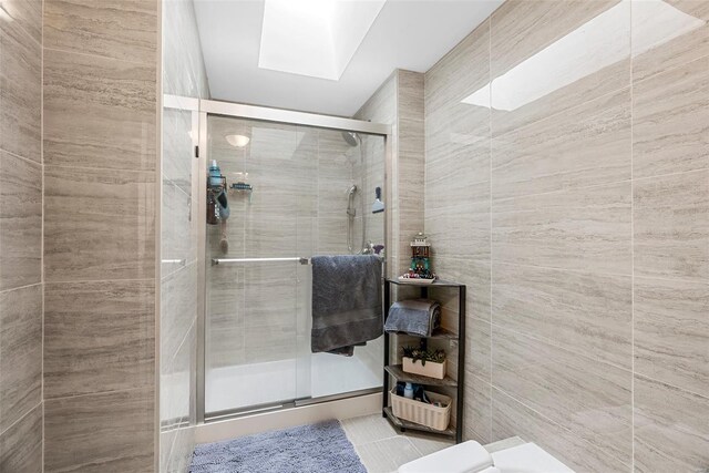bathroom featuring a skylight, tile walls, and a stall shower