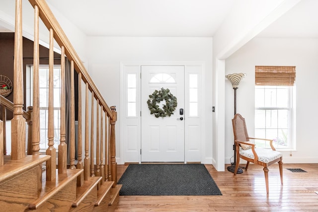foyer with baseboards, visible vents, light wood finished floors, and stairs