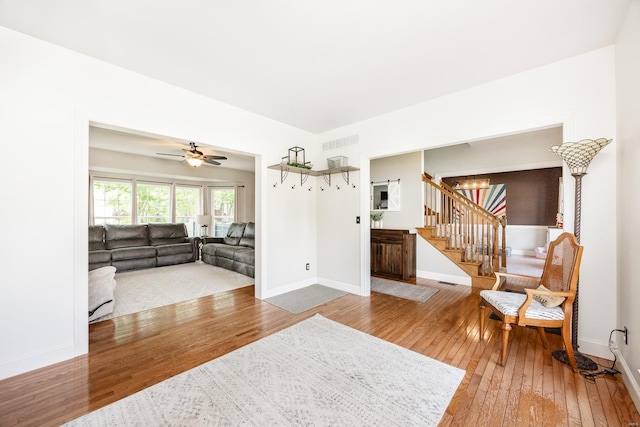 living area featuring wood-type flooring, baseboards, visible vents, and stairway
