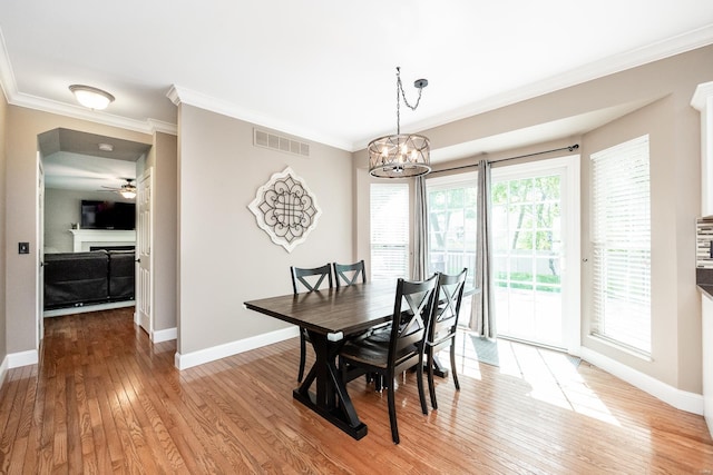 dining space featuring visible vents, ornamental molding, a fireplace, baseboards, and light wood-style floors