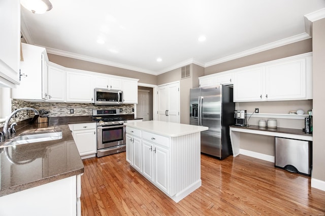 kitchen featuring appliances with stainless steel finishes, a sink, white cabinetry, a kitchen island, and visible vents