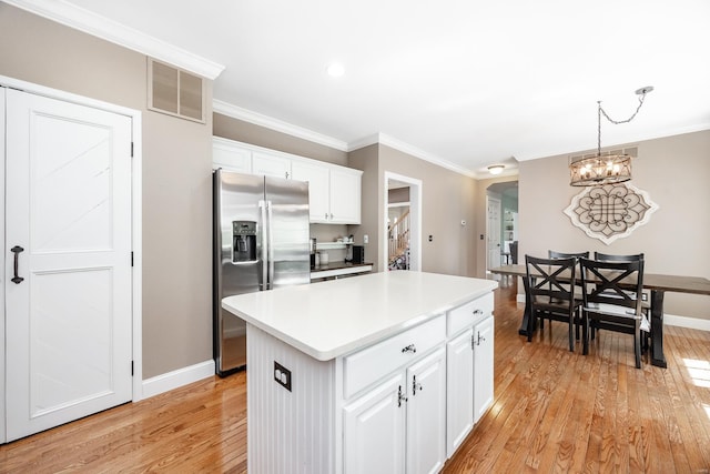kitchen with a kitchen island, visible vents, crown molding, stainless steel fridge with ice dispenser, and light wood finished floors