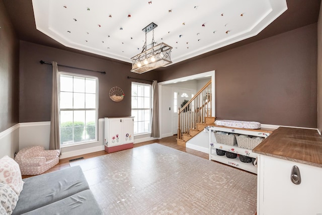 interior space featuring baseboards, a tray ceiling, wood finished floors, and stairway