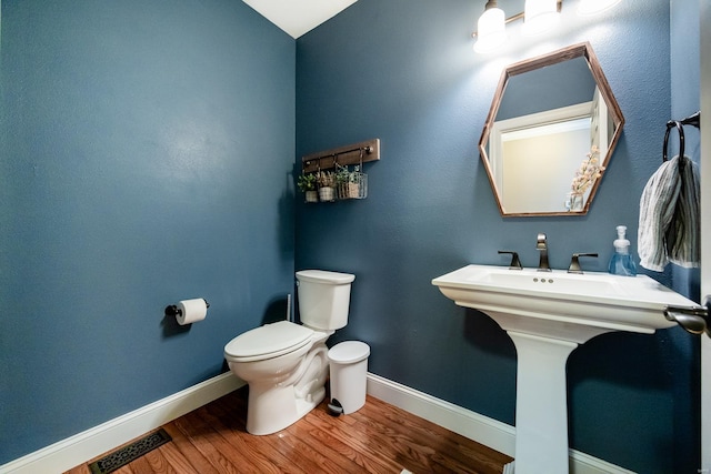 bathroom featuring visible vents, baseboards, wood finished floors, and toilet