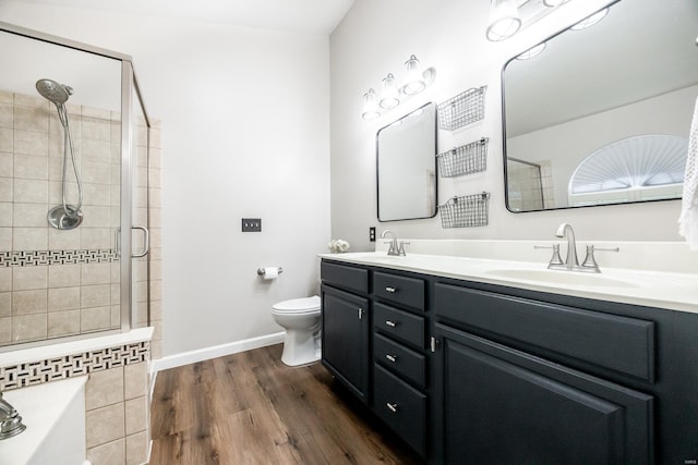 full bathroom with a sink, toilet, tiled shower, and wood finished floors