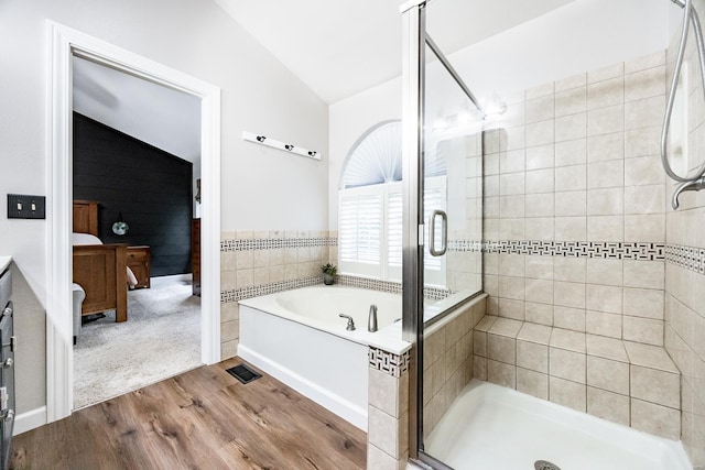 bathroom featuring vaulted ceiling, a shower stall, wood finished floors, and a garden tub