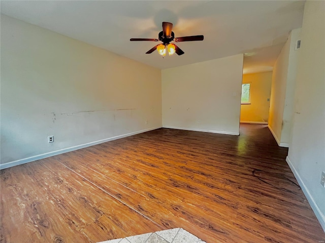 unfurnished room with baseboards, ceiling fan, visible vents, and dark wood-type flooring