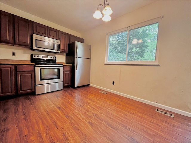 kitchen featuring a chandelier, appliances with stainless steel finishes, wood finished floors, and visible vents