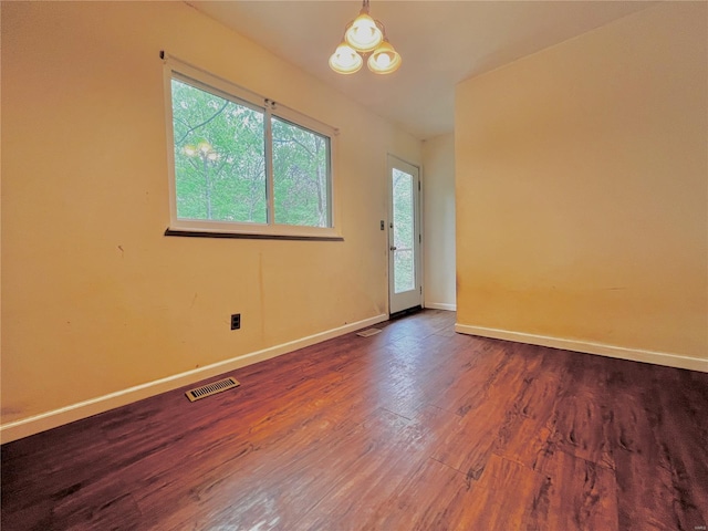 empty room featuring visible vents, baseboards, wood finished floors, and a healthy amount of sunlight