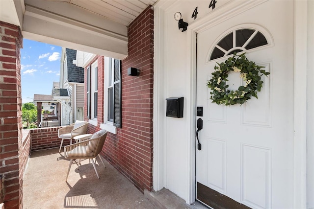 view of exterior entry featuring a porch and brick siding