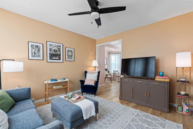 living room with baseboards, light wood-style flooring, and ceiling fan