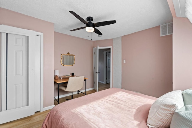 bedroom featuring visible vents, a closet, baseboards, a ceiling fan, and light wood finished floors