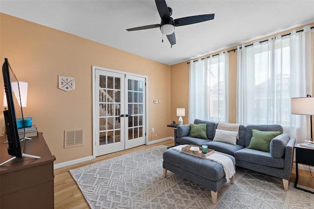 living room with visible vents, baseboards, french doors, a ceiling fan, and light wood finished floors