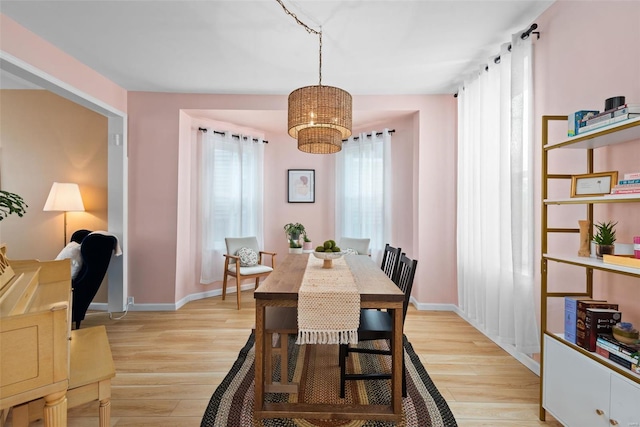 dining room featuring light wood-type flooring, baseboards, and a notable chandelier