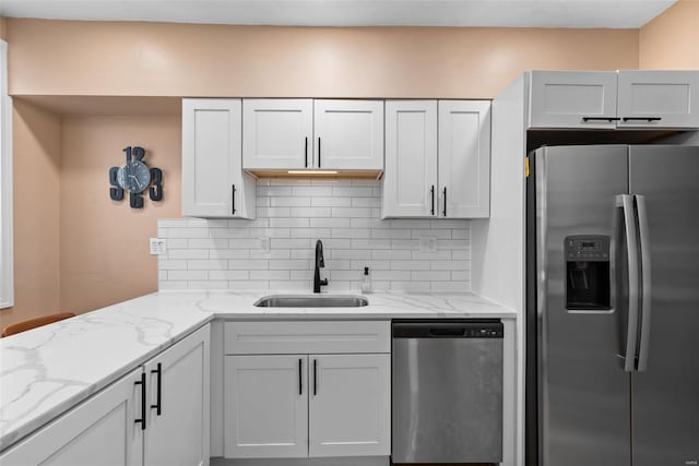 kitchen featuring a sink, decorative backsplash, appliances with stainless steel finishes, and light stone countertops