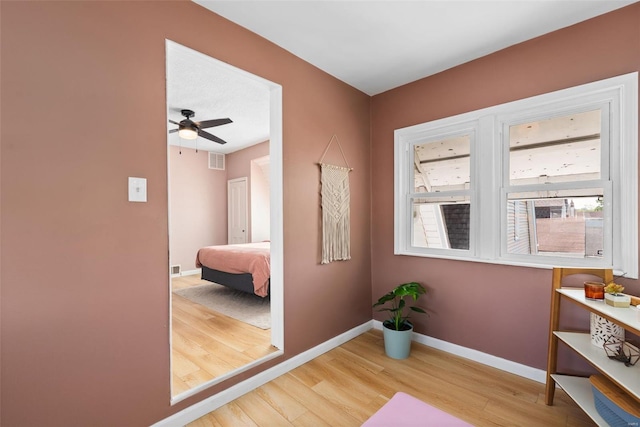 doorway to outside with baseboards, a ceiling fan, wood finished floors, and visible vents