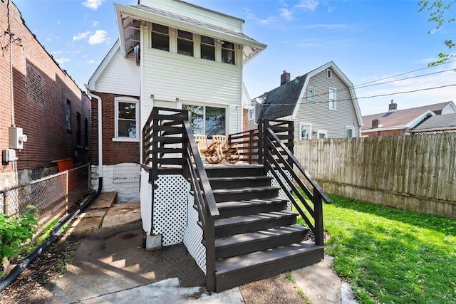 back of house with brick siding, a fenced backyard, and stairway